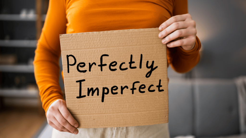 person holding a sign that says perfectly imperfect